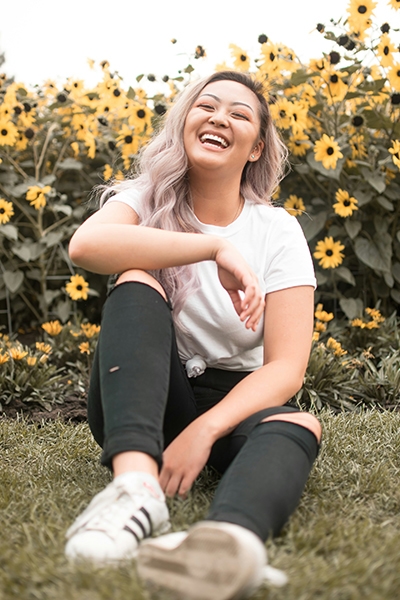 A blonde girl sitting on a grass and smiling