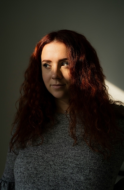 Redhead girl in the shadow smiling and looking at her right side